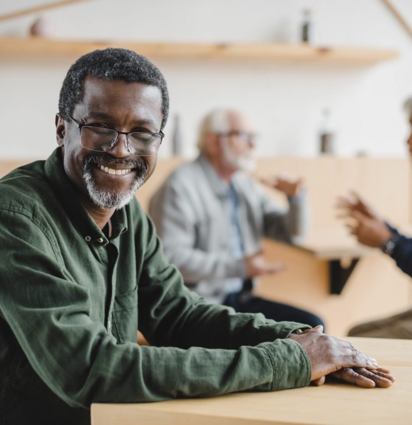happy senior african american man sitting in cafe and looking at camera